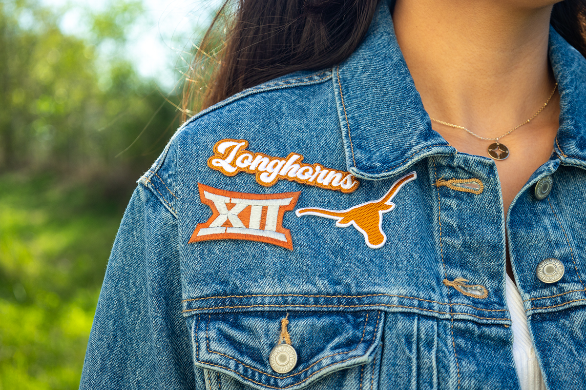 Denim jacket with 'Longhorns' and 'XII' patches, outdoors.
